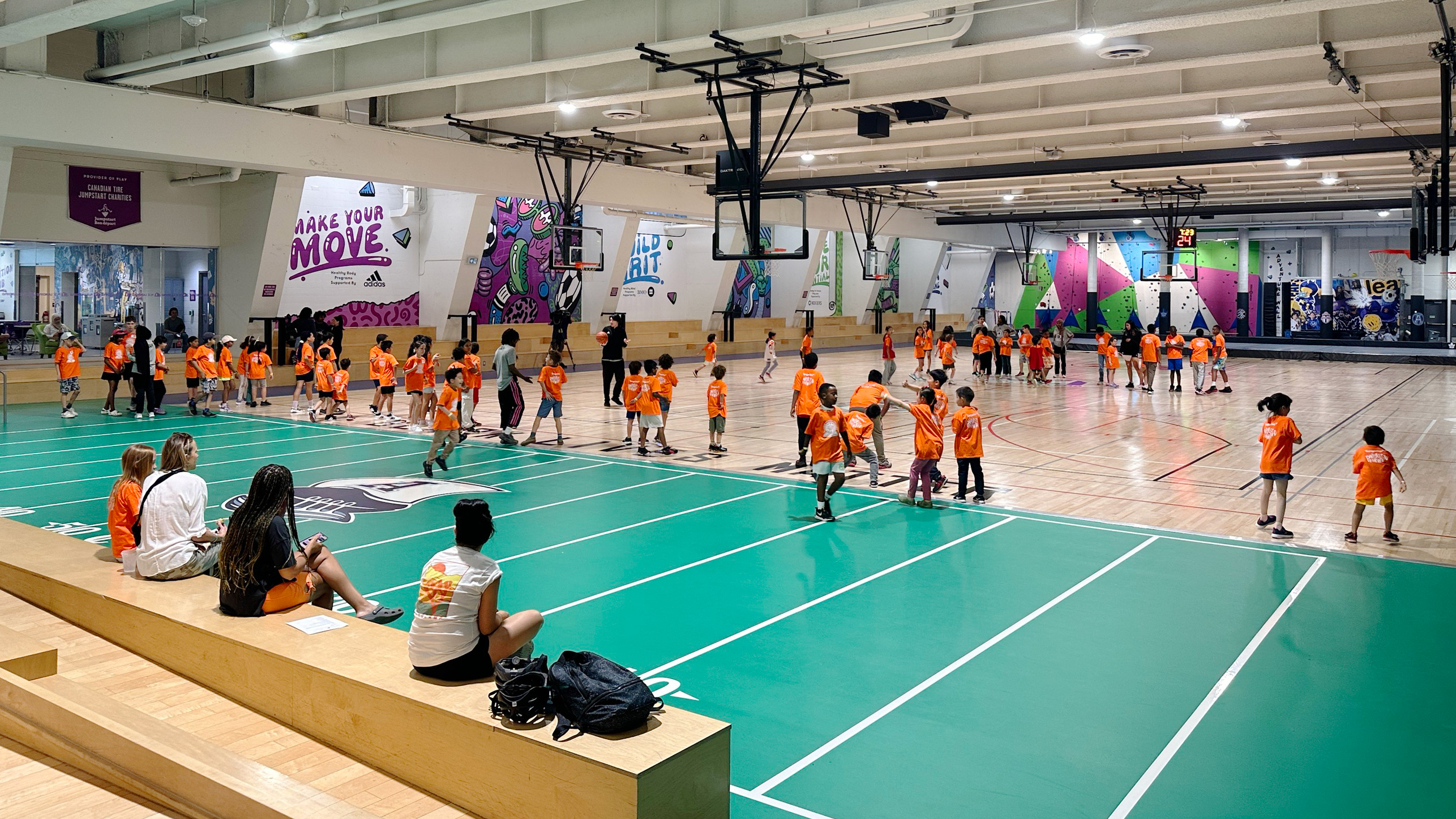 A group of children wearing orange t-shirts in a gym running around