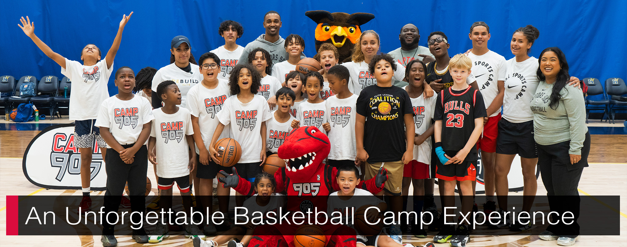 A group of children and adults with a red raptor mascot and a great horned owl mascot posing for a photo. Text reads, 