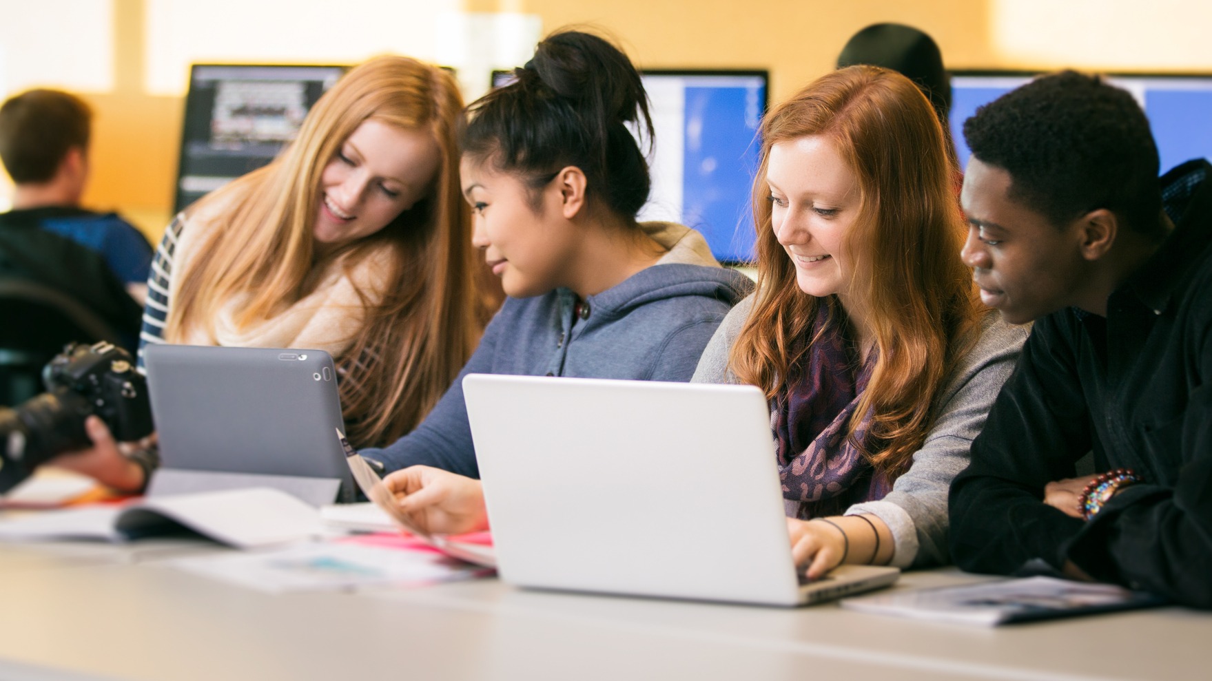 Group of students smiling looking at laptop