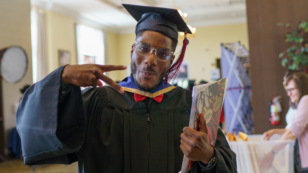 Graduate in cap and gown giving a peace sign