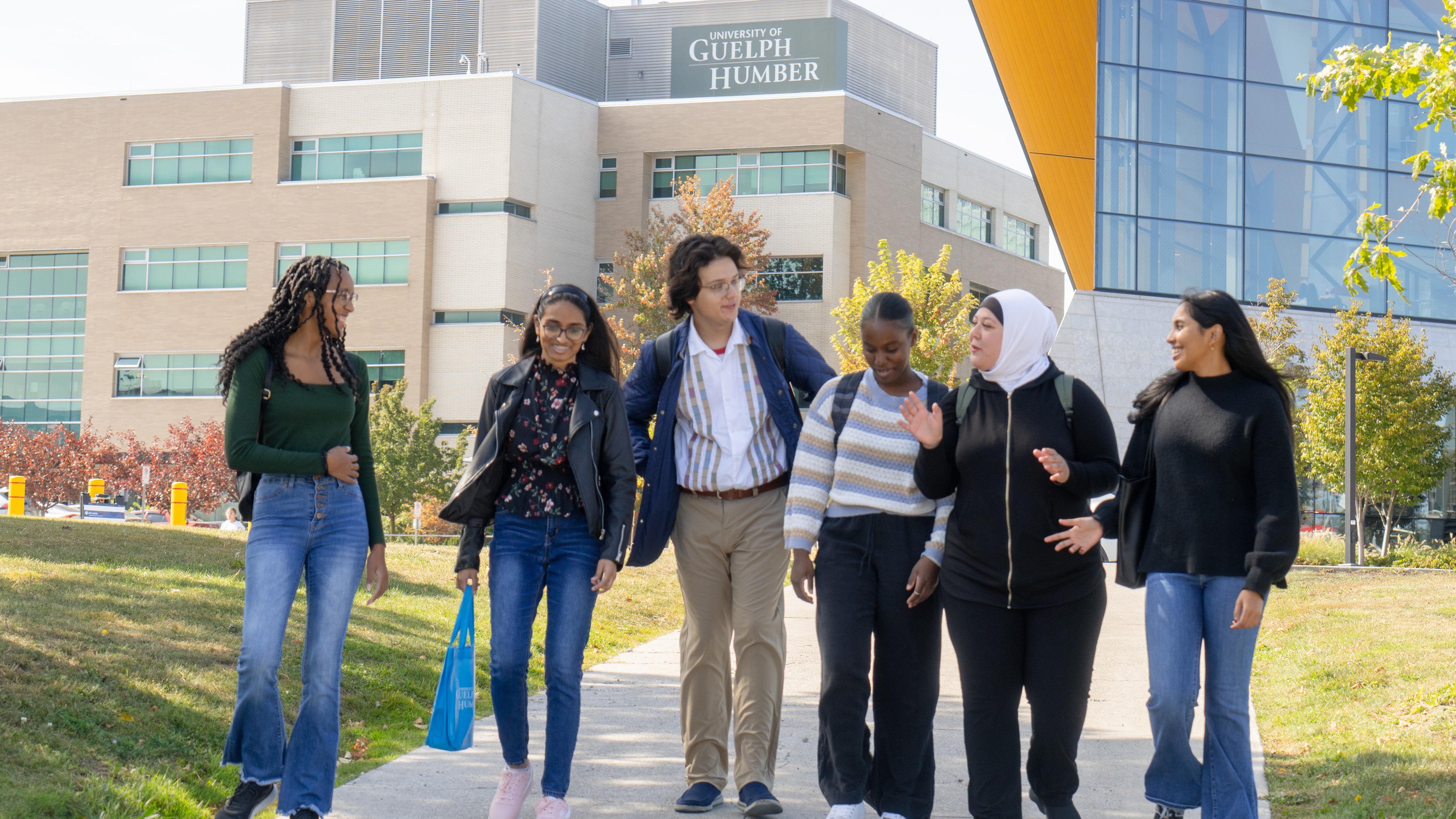 A group of students walking on a path outside of the Guelph-Humber building
