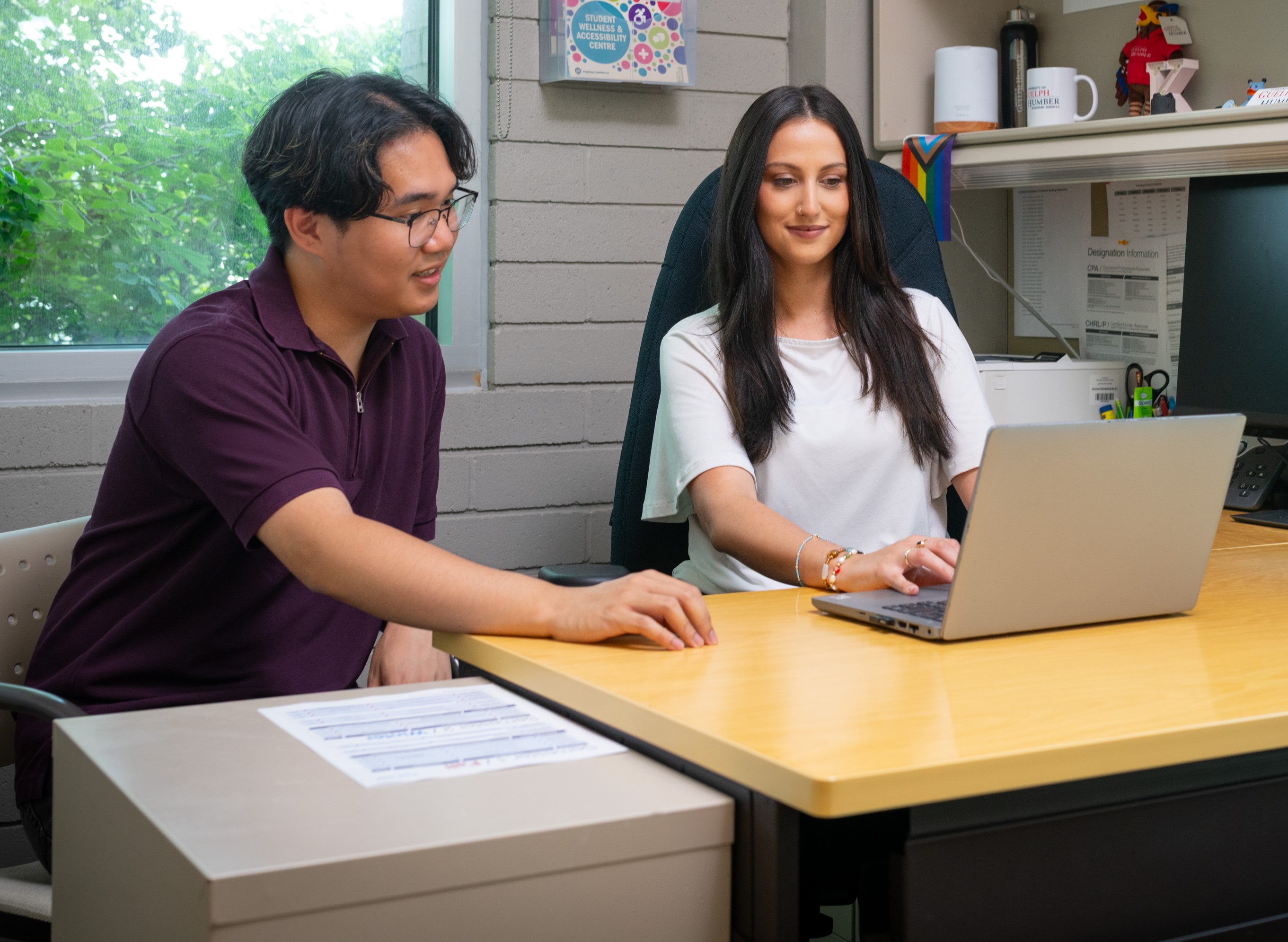 New Student Checklist (On-campus) A student sits with an Academic Advisor, both facing a laptop