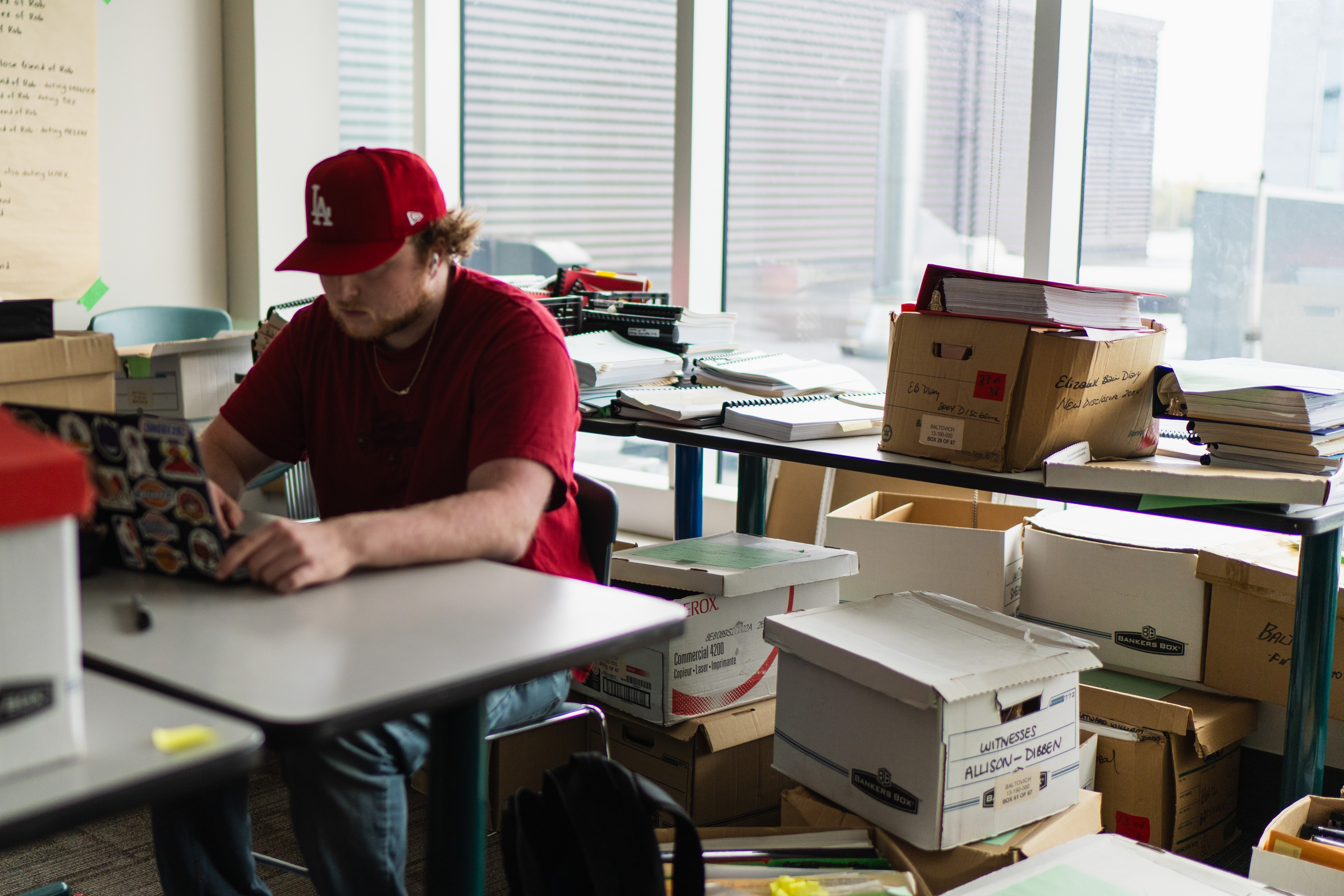 A male student on a laptop in a room filled with boxes