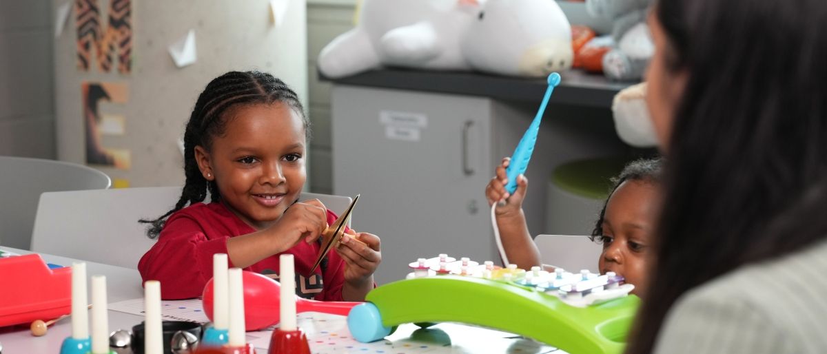 ECS banner student playing musical instruments with children