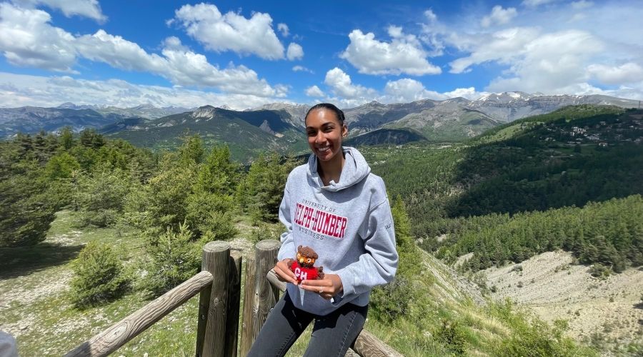 Woman wearing UofGH hoody holding mini swoop with landscape in background